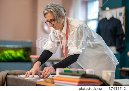 Concentrated woman standing near table drawing pattern 87453742