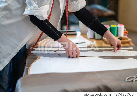 Hands of tailor laying paper pattern to fabric 87453766