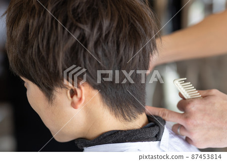 A man who has a haircut in a barber shop 87453814