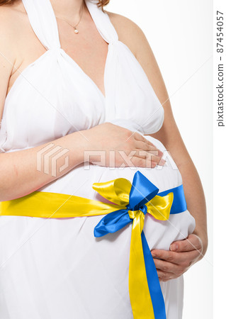 The War in Ukraine, Ukrainian conflict background. The Ukrainian flag is painting on the belly of a pregnant woman. The War in Ukraine, Ukrainian conflict background. The Ukrainian flag is painting on the belly of a pregnant woman. 87454057