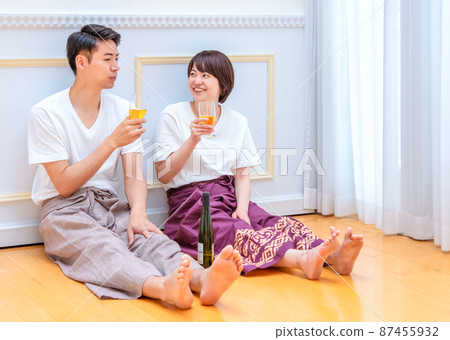 A couple sitting on the floor and tilting the glass A couple sitting on the floor and tilting the glass 87455932