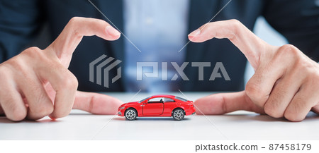 Businessman hand cover or protection red car toy on table. Car insurance, warranty, repair, Financial, banking and money concept Businessman hand cover or protection red car toy on table. Car insurance, warranty, repair, Financial, banking and money concept 87458179