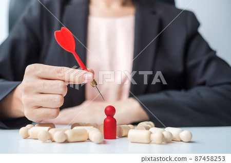 Hand holding dart over red people.Goal, target, aim, objective, leadership, Business and marketing concept Hand holding dart over red people.Goal, target, aim, objective, leadership, Business and marketing concept 87458253