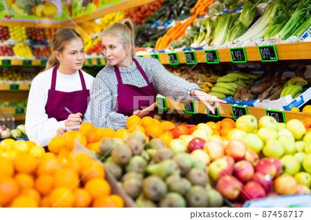 Saleswoman instructing daughter before starting work in family store 87458717