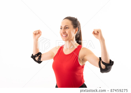 Smiling caucasian young female handball player with clenched fist standing against white background 87459275