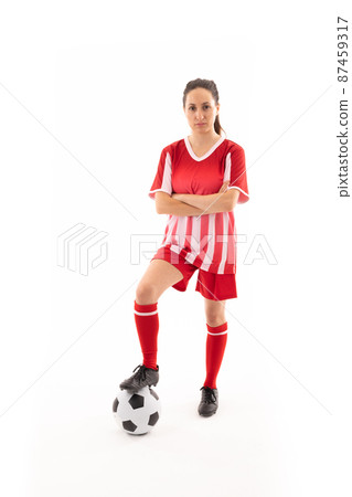Portrait of caucasian young female player standing with arms crossed and foot on soccer ball Portrait of caucasian young female player standing with arms crossed and foot on soccer ball 87459317