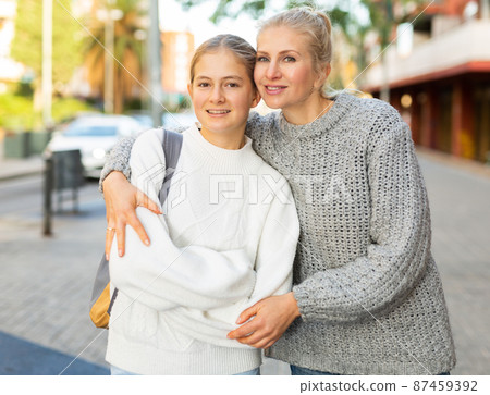 Happy woman hugging with teen daughter outdoor on city street 87459392