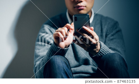 A man with a mental illness is using a smartphone 87463135