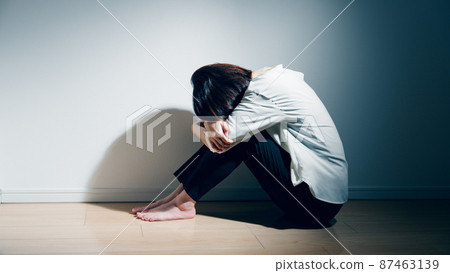 A young woman suffering from a mental illness is holding her knees A young woman suffering from a mental illness is holding her knees 87463139