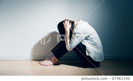 A young woman suffering from a mental illness is holding her knees A young woman suffering from a mental illness is holding her knees 87463140