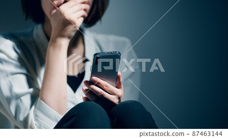 A young woman suffering from a mental illness is using a smartphone 87463144