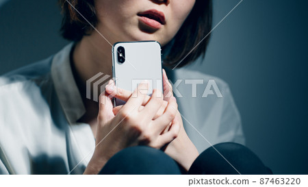 A young woman suffering from a mental illness is using a smartphone A young woman suffering from a mental illness is using a smartphone 87463220