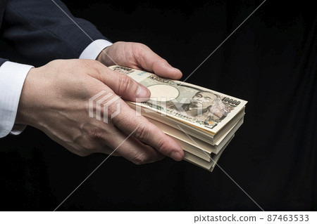 一個男人的手拿著一沓鈔票 一個男人的手拿著一沓鈔票 87463533