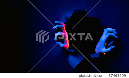 Night terror. Haunted banner. Evil ghost. Red blue neon light female monster hands breaking through torn wall isolated on dark black empty space background. Night terror. Haunted banner. Evil ghost. Red blue neon light female monster hands breaking through torn wall isolated on dark black empty space background. 87465209