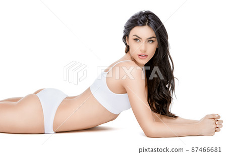 Fitness young woman with a beautiful body laying on white background 87466681