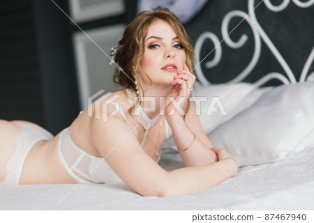 Beautiful young bride in a white lingerie. Last preparations for the wedding. Girl is waiting for the groom. 87467940