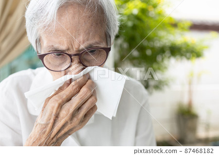 Sick asian senior woman having a cold,runny nose stuffy nose,old elderly blowing or wiping nose in a paper handkerchief,rhinitis,virus infection,sinusitis or dust allergies,nasal congestion concept 87468182