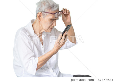 Asian senior woman with eye glasses,try to read messages,gaze at the small text on mobile phone,age related macular degeneration,blurred vision,poor eyesight problems,eye disease of the old elderly Asian senior woman with eye glasses,try to read messages,gaze at the small text on mobile phone,age related macular degeneration,blurred vision,poor eyesight problems,eye disease of the old elderly 87468683