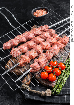 Raw Shish kebab from mince lamb and beef meat, turkish adana kebab on Skewers. Black background. Top view 87470253