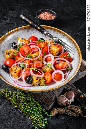 Vegetarian salad Panzanella with tomatoes, onion and bread Croutons. Black background. Top view Vegetarian salad Panzanella with tomatoes, onion and bread Croutons. Black background. Top view 87470261