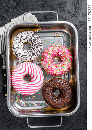 Assorted donuts with chocolate, pink glazed and sprinkles Doughnut. Black background. Top view Assorted donuts with chocolate, pink glazed and sprinkles Doughnut. Black background. Top view 87470285