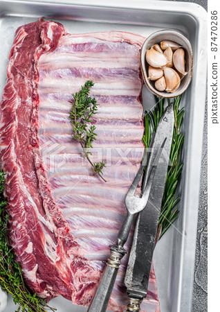 Raw uncooked rack of mutton lamb ribs in baking dish. White background. Top view 87470286