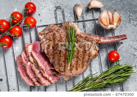 BBQ roasted sliced rib eye Tomahawk beef steak on grill. Gray background. Top view BBQ roasted sliced rib eye Tomahawk beef steak on grill. Gray background. Top view 87470300