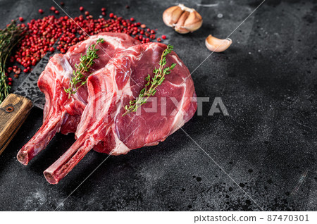 Raw Tomahawk rib veal steaks on butcher meat cleaver. Black background. Top view. Copy space Raw Tomahawk rib veal steaks on butcher meat cleaver. Black background. Top view. Copy space 87470301