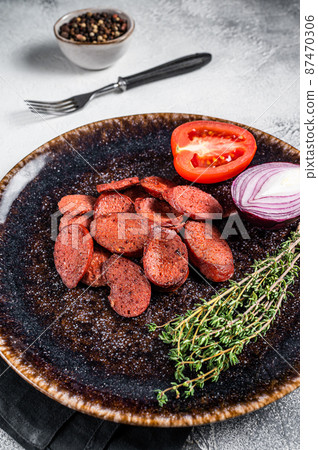 Fried sausage sucuk from beef meat on a plate with herbs. White background. Top view 87470306