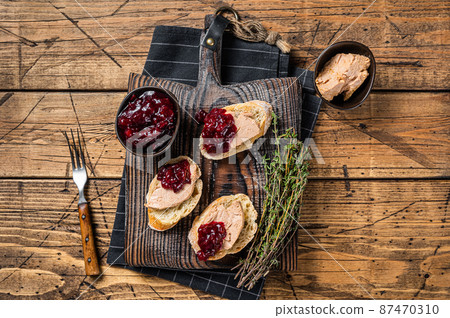 French cuisine Foie gras toasts, goose liver pate and lingonberry marmalade. wooden background. Top view French cuisine Foie gras toasts, goose liver pate and lingonberry marmalade. wooden background. Top view 87470310