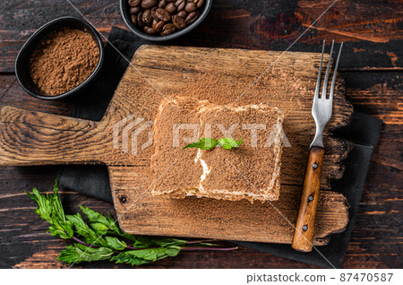 Italian dessert Tiramisu cake with cocoa and mint on a wooden board. Dark Wooden background. Top view 87470587