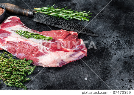 Fresh Raw lamb or goat shoulder meat with butcher knife. Black background. Top view. Copy space Fresh Raw lamb or goat shoulder meat with butcher knife. Black background. Top view. Copy space 87470599