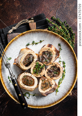 Baked marrow veal beef bones in plate with thyme and herbs. Dark background. Top view Baked marrow veal beef bones in plate with thyme and herbs. Dark background. Top view 87470709