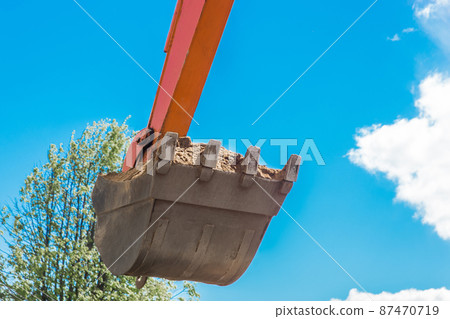 Excavation works. Tractor bucket digging the ground on a construction site against the sky 87470719