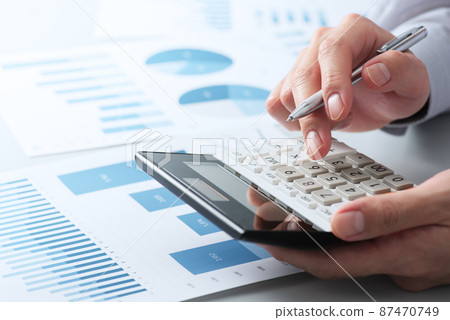 財務分析的圖像。舉手用計算器計算。辦公桌上的多份報告。 87470749
