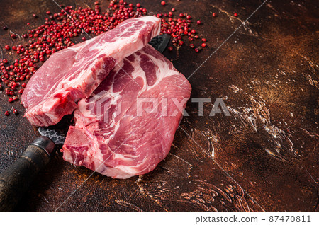 Pork loin steak from raw neck fillet meat on butcher knife. Dark background. Top view. Copy space Pork loin steak from raw neck fillet meat on butcher knife. Dark background. Top view. Copy space 87470811