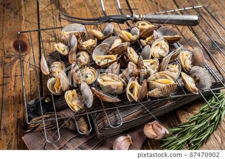 Cooked shells Clams, vongole on a grill with garlic and rosemary. Wooden background. Top view 87470902