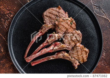 BBQ Grilled lamb chops steaks in a plate. Dark background. Top view 87471082