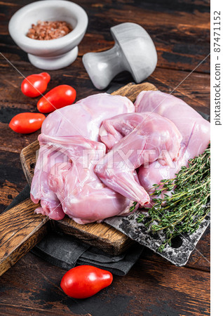 Raw hare legs on a butcher board with thyme. Dark wooden background. Top view Raw hare legs on a butcher board with thyme. Dark wooden background. Top view 87471152