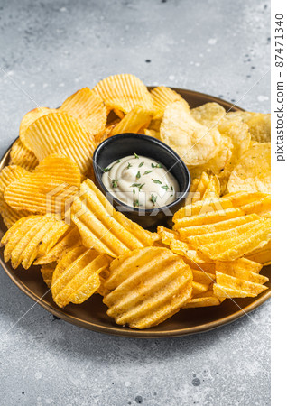 Variety of Potato chips in a plate served with dip sauce. Gray background. Top view 87471340