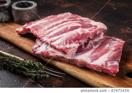 Raw pork spare loin ribs St Louis on wooden board with herbs. Dark background. Top view Raw pork spare loin ribs St Louis on wooden board with herbs. Dark background. Top view 87471439