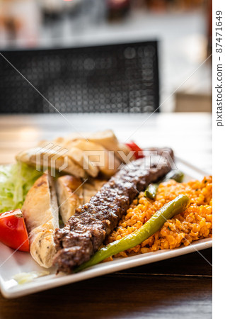 Traditional Turkish Adana kebab or kebap meat food with marinated peppers, bread and rice pilaf. Top view Traditional Turkish Adana kebab or kebap meat food with marinated peppers, bread and rice pilaf. Top view 87471649