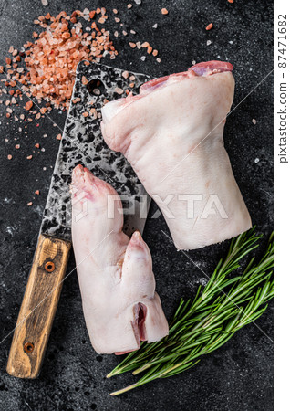 Butcher shop - Raw pork hoof, knuckle, feet on a cutting board. Black background. Top view 87471682