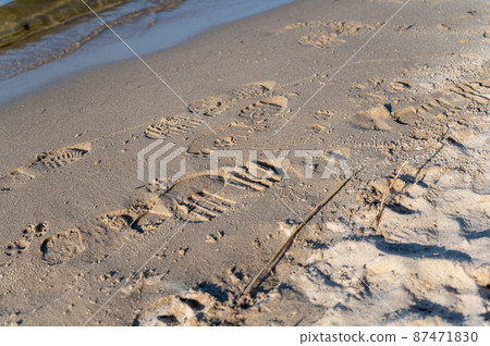 Footprints of different people on the wet sand. The shore of the sea or river with many footprints. Selective focus. Footprints of different people on the wet sand. The shore of the sea or river with many footprints. Selective focus. 87471830