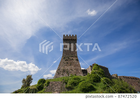 Brick tower Rocca of Radocofani with the cloudy sky background on a summer day, Tuscany, Italy Brick tower Rocca of Radocofani with the cloudy sky background on a summer day, Tuscany, Italy 87472520