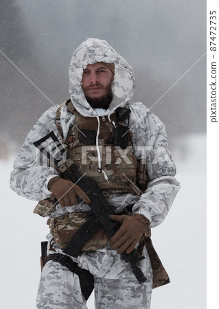 Soldier in winter camouflaged uniform in Modern warfare army on a snow day on forest battlefield with a rifle. Model face very similar to Ukraine prime minister. 87472735