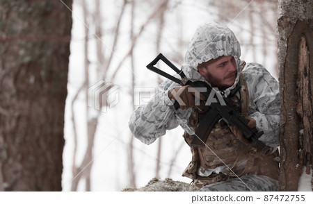 Soldier in winter camouflaged uniform in Modern warfare army on a snow day on forest battlefield with a rifle. Model face very similar to Ukraine prime minister. 87472755