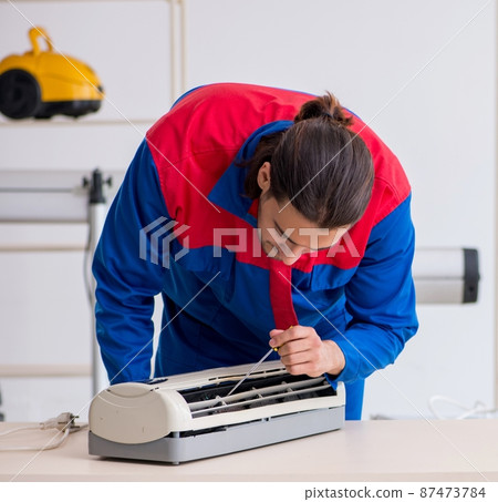 Young male contractor repairing air-conditioner at workshop Young male contractor repairing air-conditioner at workshop 87473784