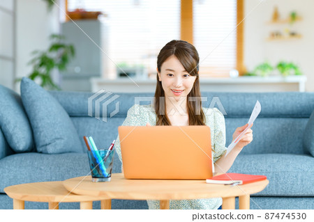 A young business woman in telework explaining in a chat with a document in her living room 87474530