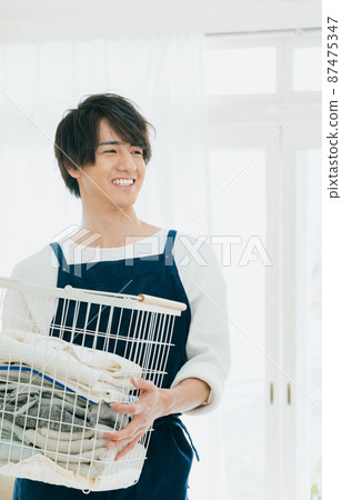Young man cleaning up the laundry 87475347